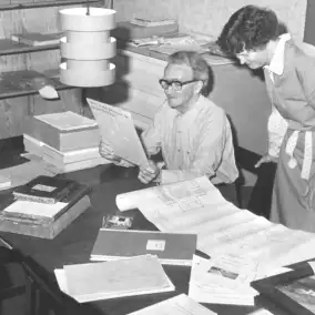 To personer ser på dokumenter og protokoller ved et skrivebord