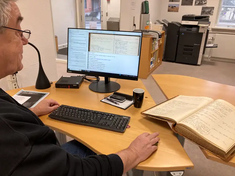 H.C. Enevoldsen sidder foran computeren på arkivet og er ved at transkribere sognerådsprotokollen fra Søborg-Gilleleje Kommune fra 1940-1948.